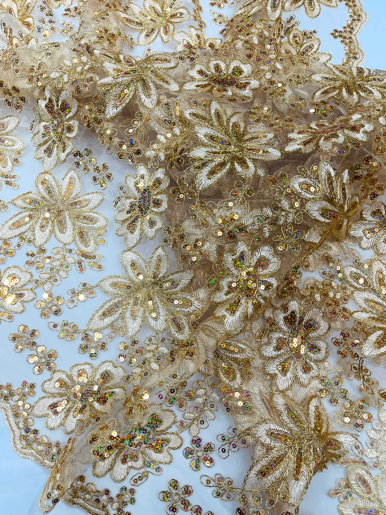 Metallic floral lace design embroidered with holographic sequins on a mesh 54” wide.