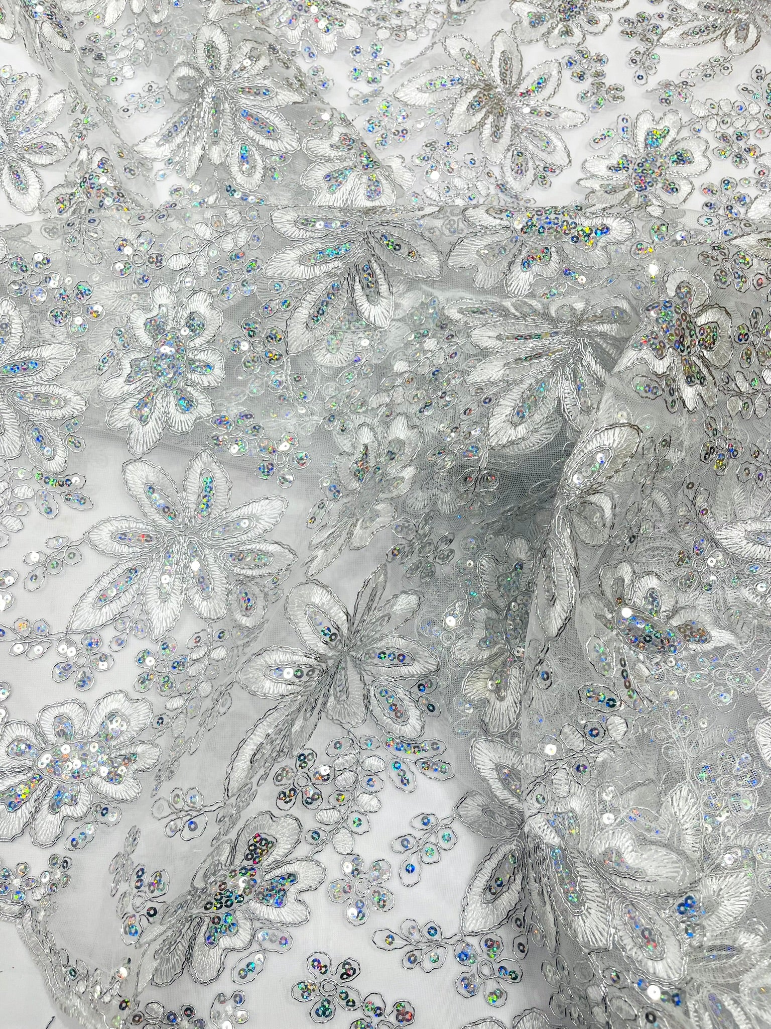Metallic floral lace design embroidered with holographic sequins on a mesh 54” wide.