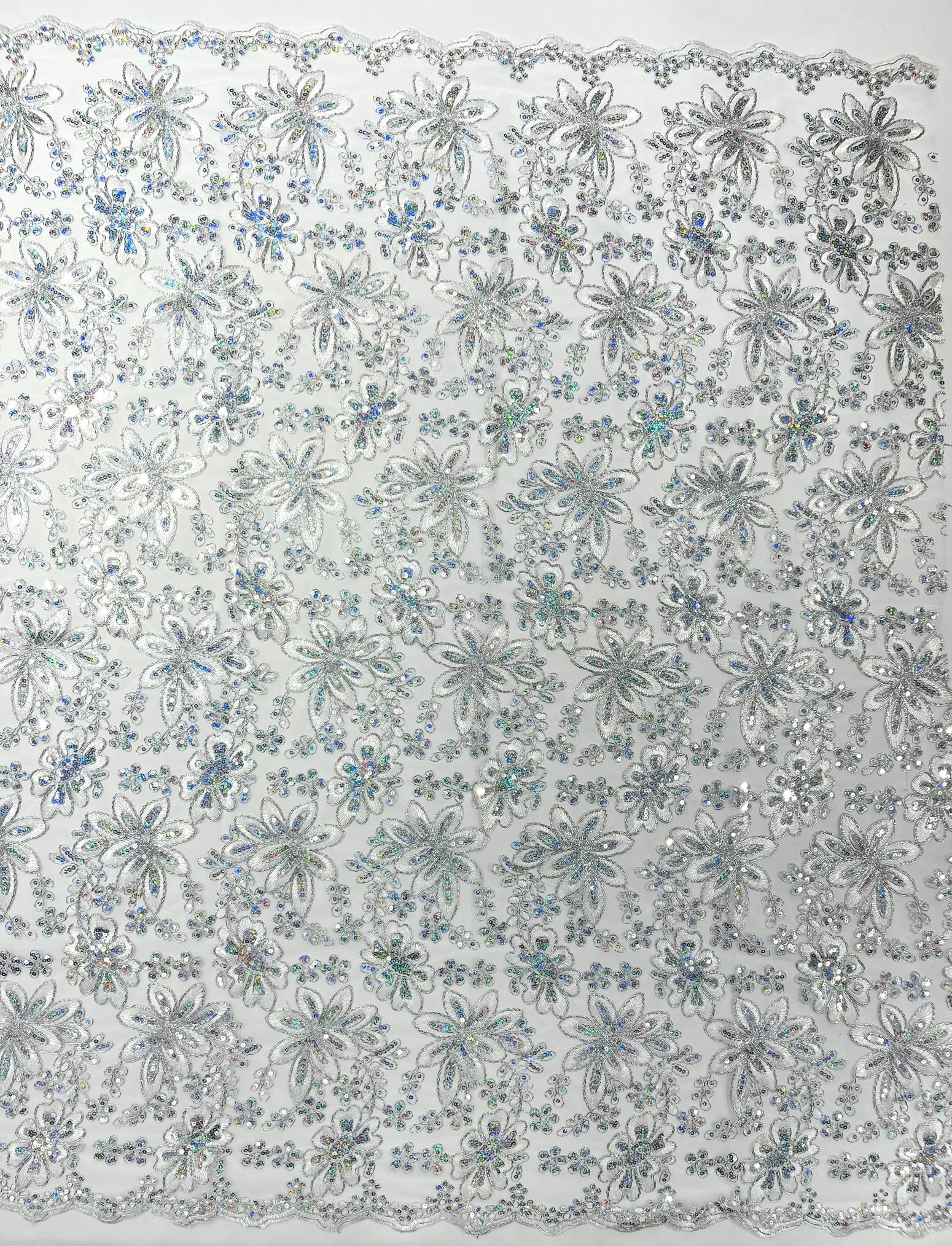 Metallic floral lace design embroidered with holographic sequins on a mesh 54” wide.